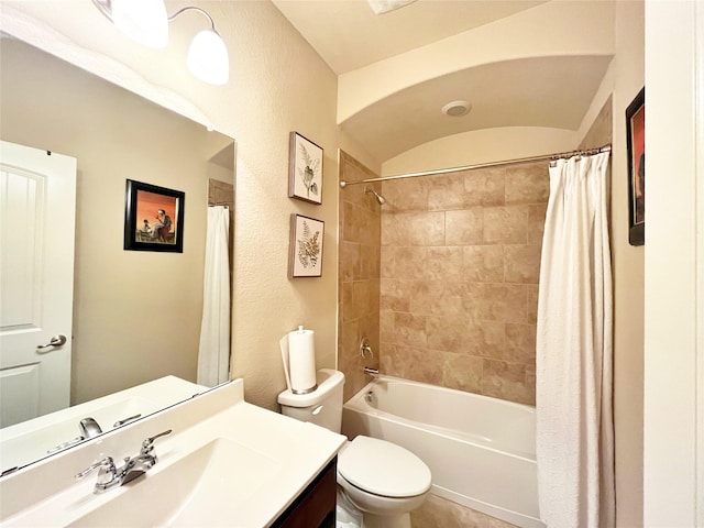 bathroom featuring shower / bath combo, toilet, a textured wall, and vanity
