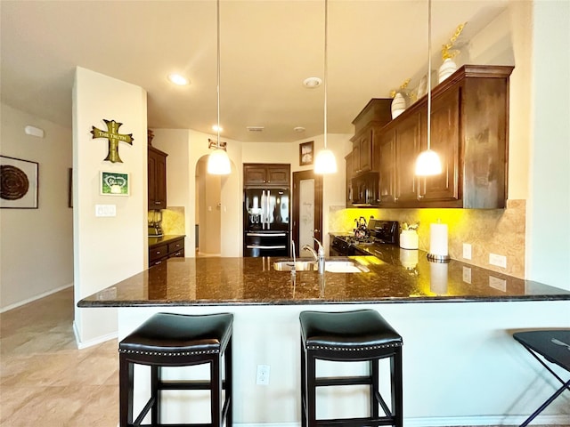 kitchen with a peninsula, dark stone counters, a sink, and black appliances