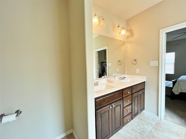 ensuite bathroom featuring ensuite bath, a sink, double vanity, and baseboards