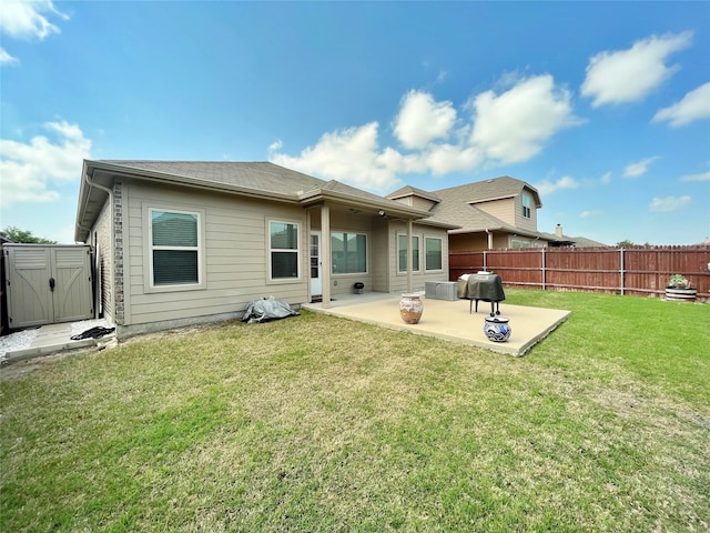 rear view of property featuring a patio area, a fenced backyard, a yard, and a shed