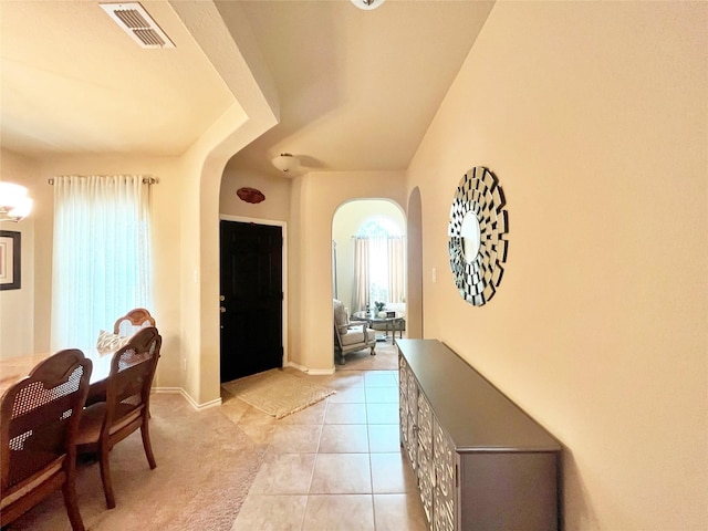 entrance foyer featuring baseboards, arched walkways, visible vents, and light tile patterned floors