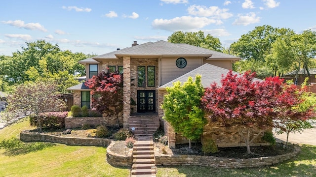 traditional-style home with brick siding, a front lawn, roof with shingles, and a chimney