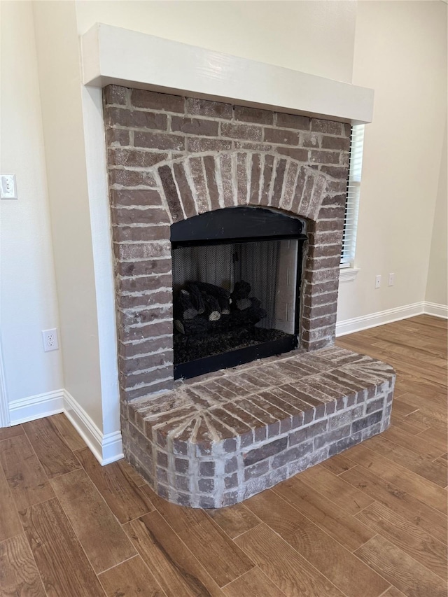 room details with baseboards, wood finished floors, and a fireplace