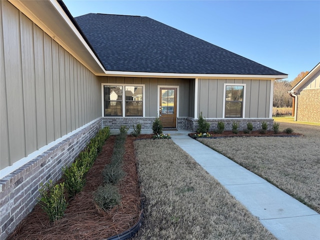 view of front facade with brick siding, a shingled roof, and a front yard