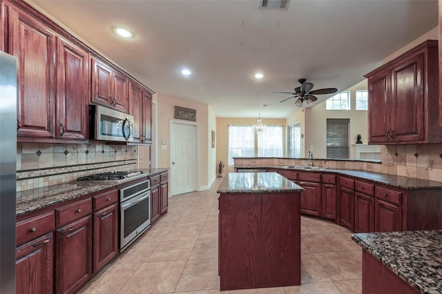 kitchen with a peninsula, tasteful backsplash, stainless steel appliances, and a sink