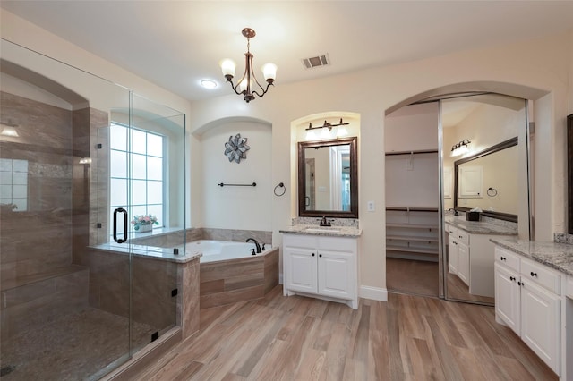bathroom featuring a bath, visible vents, a stall shower, and wood finished floors