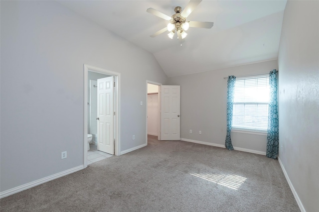 unfurnished bedroom featuring carpet flooring, baseboards, a spacious closet, lofted ceiling, and connected bathroom