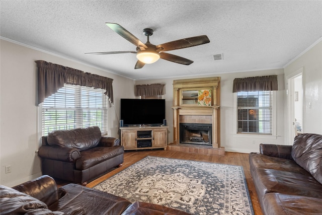 living area featuring plenty of natural light, ornamental molding, a ceiling fan, and a textured ceiling