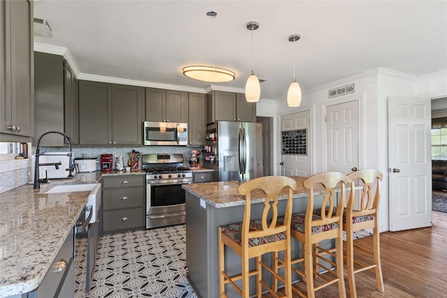 kitchen with crown molding, backsplash, appliances with stainless steel finishes, and a sink