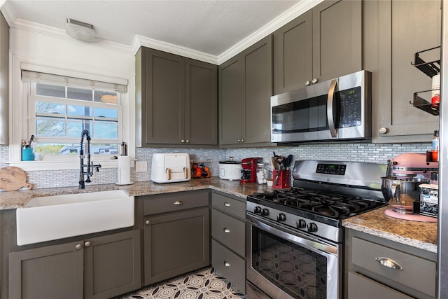 kitchen with crown molding, appliances with stainless steel finishes, a sink, decorative backsplash, and gray cabinetry