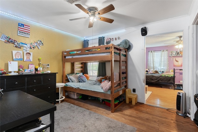 bedroom with multiple windows, ornamental molding, a ceiling fan, and wood finished floors