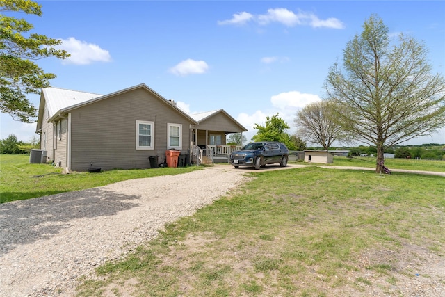 view of front of property with a porch, central AC unit, a front lawn, and gravel driveway