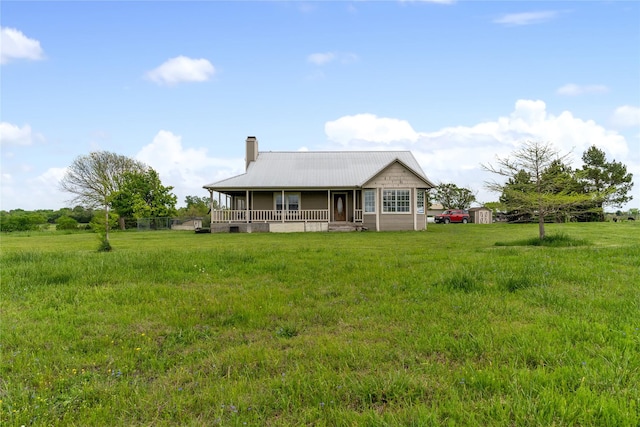 back of property featuring covered porch, a chimney, and metal roof