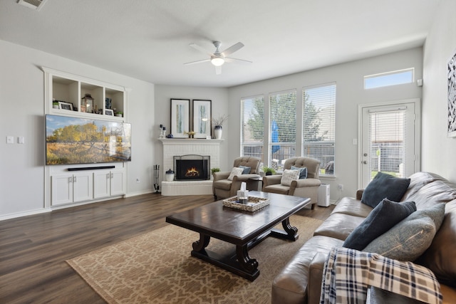 2820 Lone Ranger Trl, Little Elm, TX 75068 - living area featuring ceiling fan, dark wood finished floors, a brick fireplace, and baseboards
