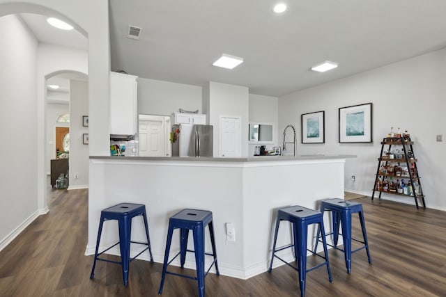 2820 Lone Ranger Trl, Little Elm, TX 75068 - kitchen with freestanding refrigerator, arched walkways, dark wood finished floors, white cabinetry, and a kitchen bar