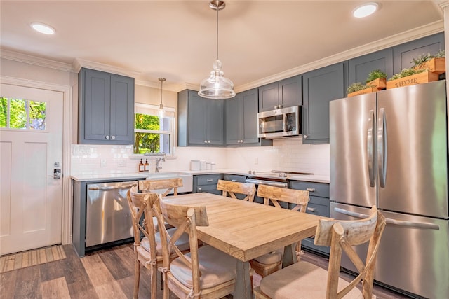 kitchen with stainless steel appliances, dark wood finished floors, backsplash, crown molding, and light countertops