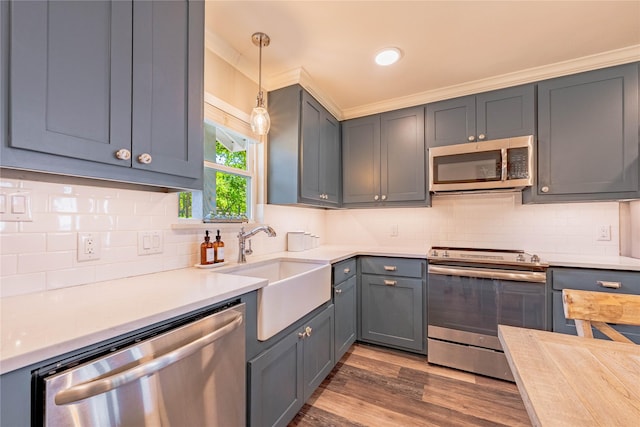 kitchen featuring a sink, stainless steel appliances, light countertops, backsplash, and dark wood-type flooring