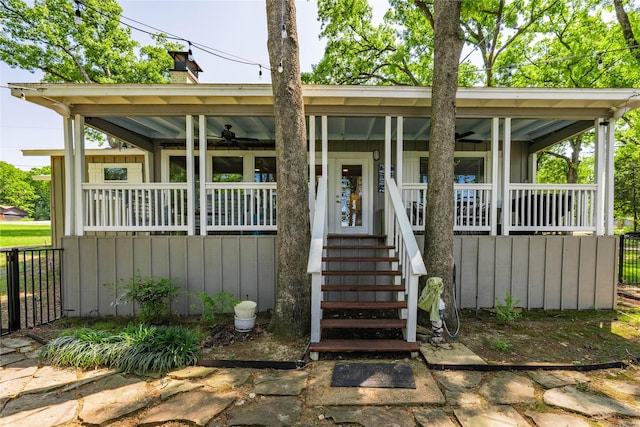 view of front of property with a chimney, a porch, a ceiling fan, and board and batten siding