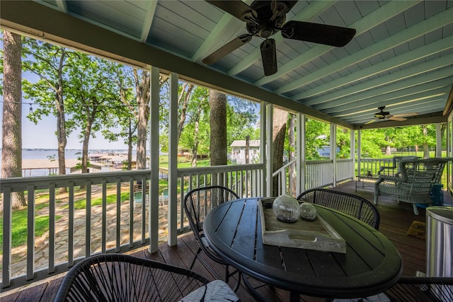 sunroom / solarium featuring beam ceiling, a ceiling fan, outdoor dining area, and a water view