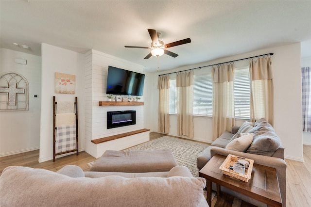 14620 Serrano Ridge Rd, Fort Worth, TX 76052 - living room with ceiling fan, light wood-style flooring, a glass covered fireplace, and baseboards