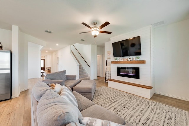 14620 Serrano Ridge Rd, Fort Worth, TX 76052 - living room with light wood-style floors, a glass covered fireplace, stairs, a ceiling fan, and baseboards