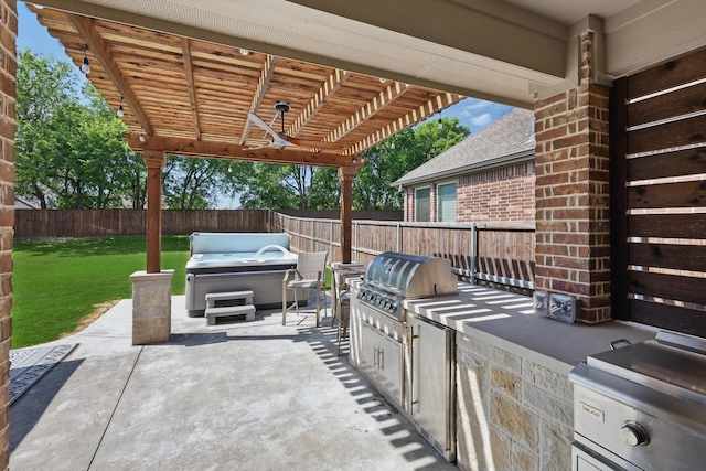 view of patio featuring a fenced backyard, a hot tub, grilling area, and an outdoor kitchen