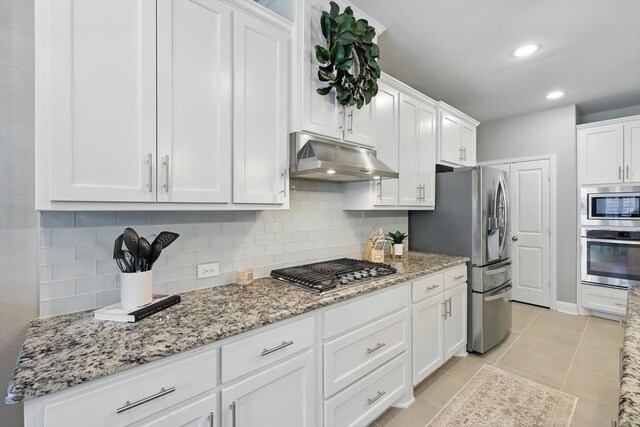 kitchen with appliances with stainless steel finishes, backsplash, under cabinet range hood, and white cabinetry