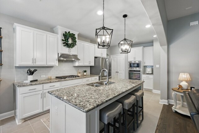 kitchen featuring white cabinets, a sink, stainless steel appliances, backsplash, and under cabinet range hood