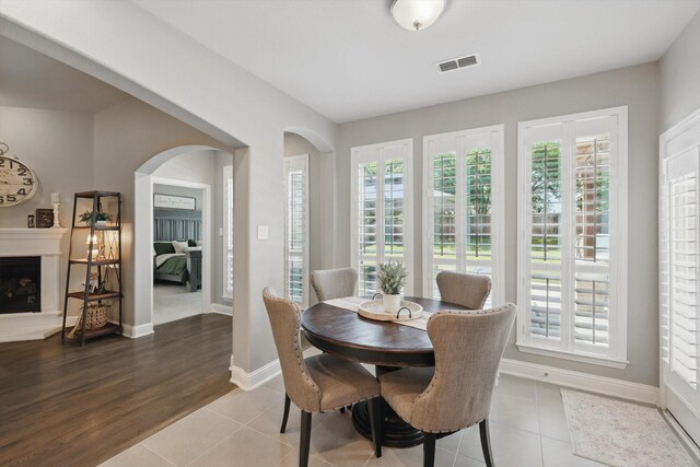tiled dining room with arched walkways, baseboards, visible vents, and a wealth of natural light