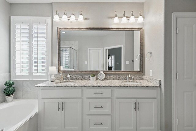 full bathroom featuring double vanity, a sink, a bath, and a shower stall