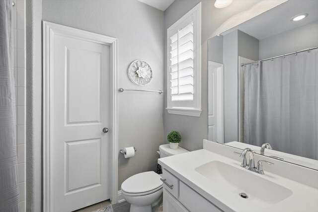 full bath featuring toilet, a shower with shower curtain, and vanity