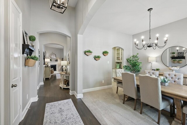 dining area featuring dark wood-style flooring, arched walkways, and an inviting chandelier