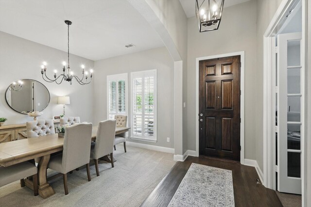 entrance foyer with visible vents, baseboards, a notable chandelier, and dark wood finished floors