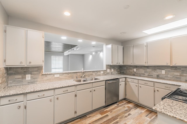 kitchen with recessed lighting, light wood finished floors, dishwasher, a sink, and a skylight