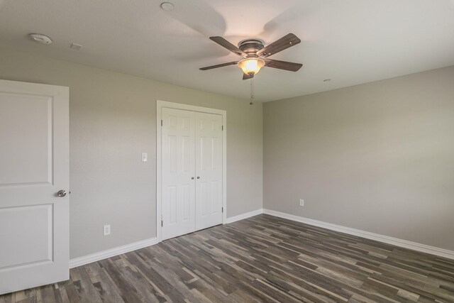 unfurnished bedroom with a ceiling fan, baseboards, dark wood-style floors, and a closet