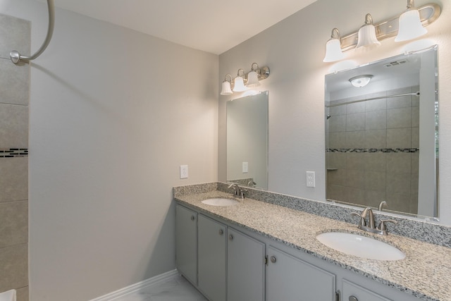 full bathroom featuring double vanity, marble finish floor, baseboards, and a sink