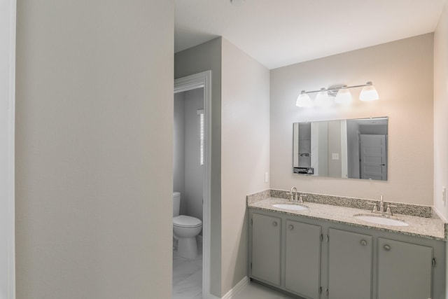 bathroom featuring double vanity, marble finish floor, toilet, and a sink