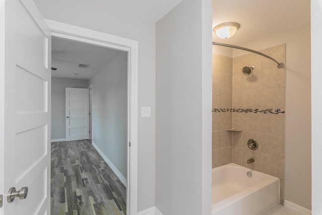 full bathroom with wood finished floors, visible vents, baseboards, and shower / bathtub combination