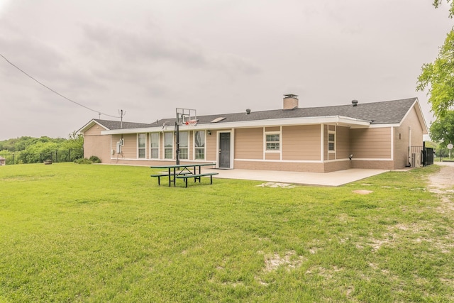 back of property featuring a chimney, fence, a yard, a patio, and brick siding