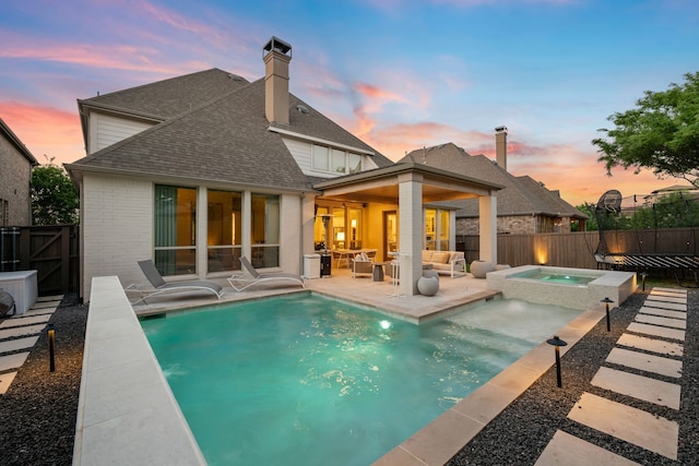 back of property with brick siding, a patio, a fenced in pool, and an in ground hot tub