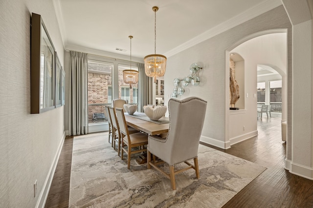 dining space with arched walkways, baseboards, a chandelier, wood finished floors, and ornamental molding