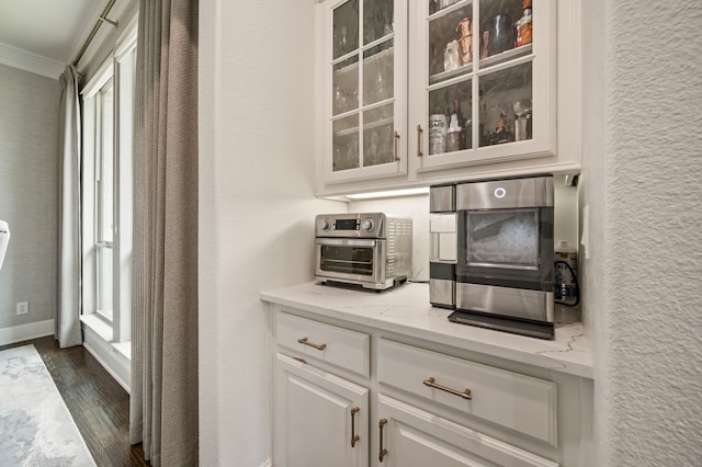 bar with a toaster, baseboards, ornamental molding, and dark wood-type flooring