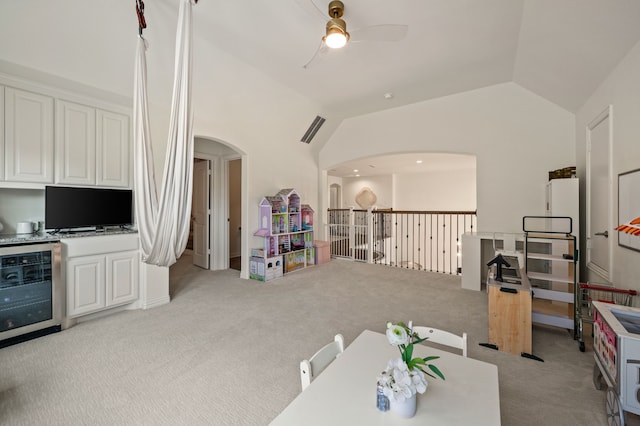 playroom with vaulted ceiling, beverage cooler, ceiling fan, arched walkways, and light carpet