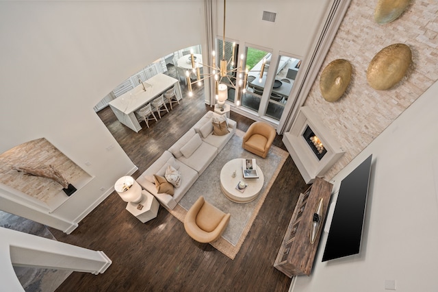 living area featuring an inviting chandelier, wood finished floors, a high ceiling, and visible vents