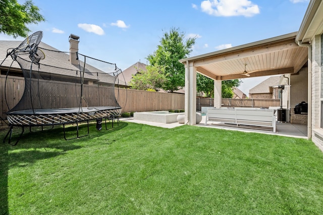 view of yard with a fenced backyard, ceiling fan, a patio area, and a trampoline