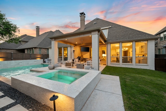 back of house with a fenced backyard, an in ground hot tub, a yard, a patio, and an outdoor living space
