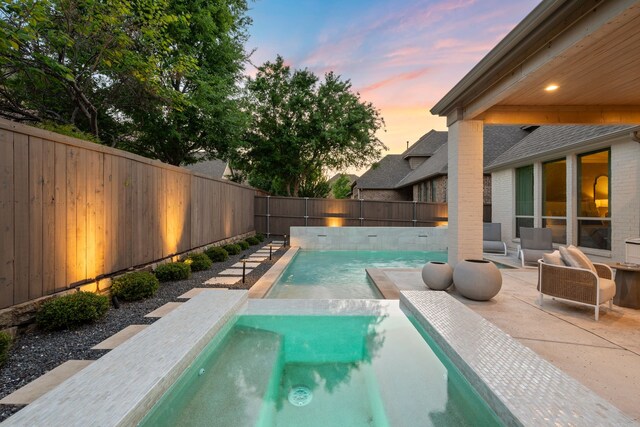pool at dusk featuring a fenced backyard, a fenced in pool, and a patio