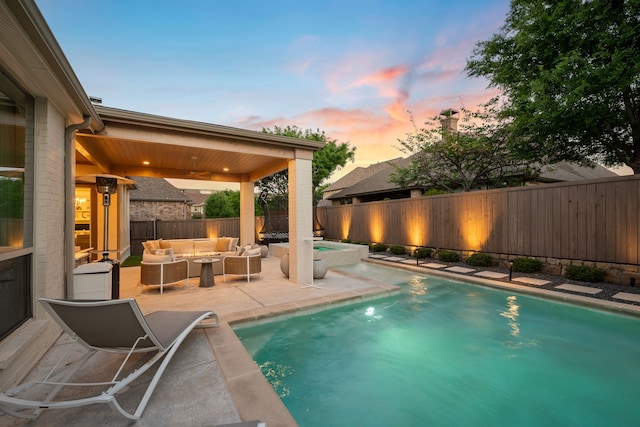 pool at dusk with a fenced backyard, a patio area, a ceiling fan, an outdoor hangout area, and a pool with connected hot tub