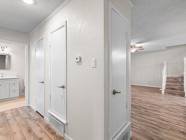 13514 Onyx Ln, Farmers Branch, TX 75234 - corridor with stairway, visible vents, crown molding, light wood-style flooring, and a textured ceiling