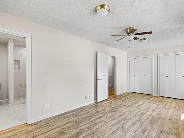 13514 Onyx Ln, Farmers Branch, TX 75234 - unfurnished bedroom featuring two closets, wood finished floors, and a textured ceiling